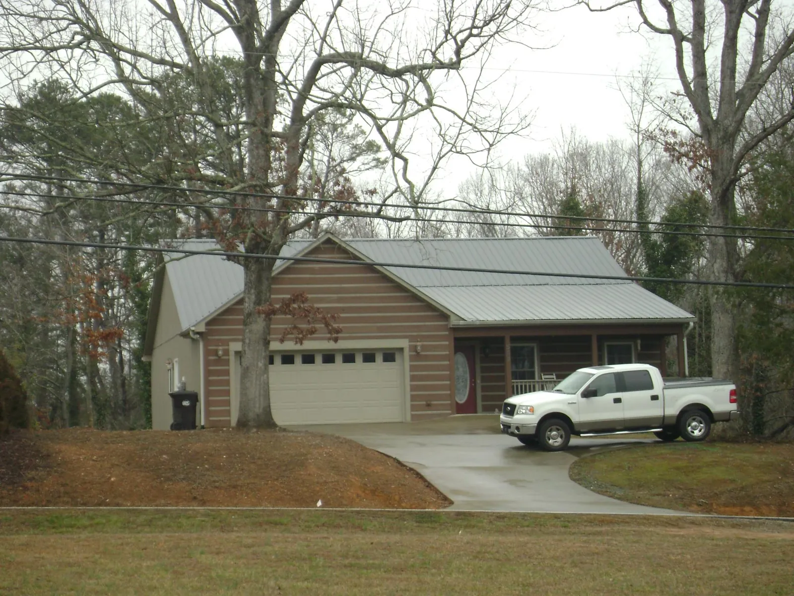Gray metal roof on a log sided house with an attached two car garage in Alexandria